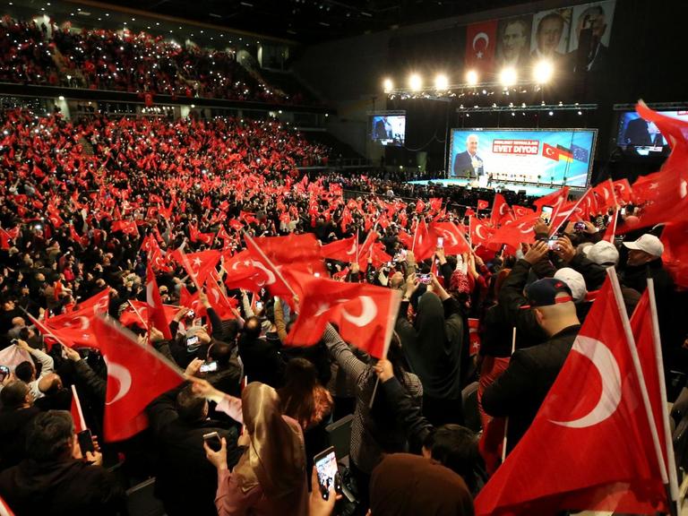 Teilnehmer bei einer Veranstaltung mit dem türkischen Ministerpräsidenten Yildirim in Oberhausen halten türkische Fahnen in den Händen.