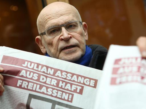 Günter Wallraff hält Blätter hoch, auf denen steht: "Julian Assange aus der Haft freilassen!".