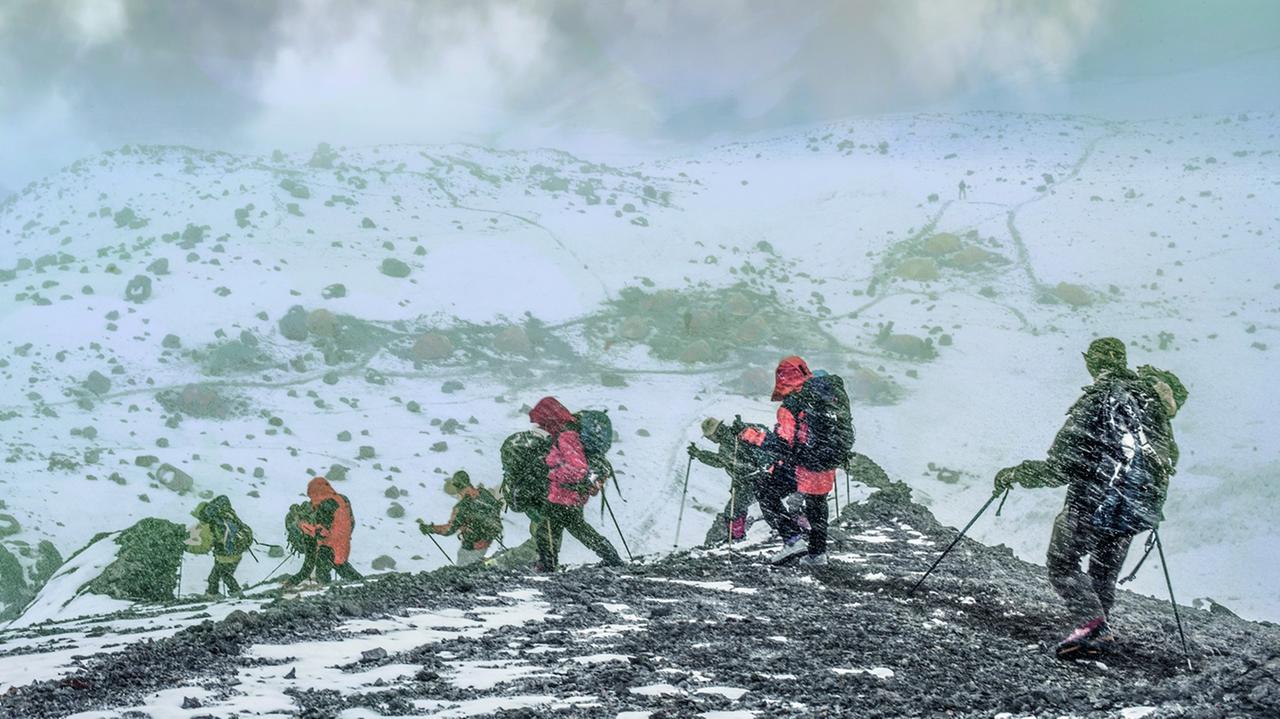 Mehrere Bergsteiger in voller Ausrüstung klettern über einen verschneiten Pass. Mehrere Bergsteiger in voller Ausrüstung klettern über einen verschneiten Pass.