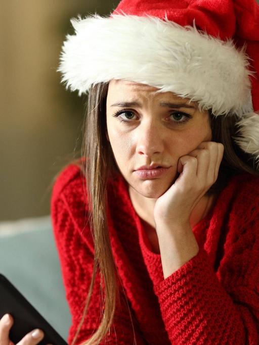Eine traurig dreinblickende Frau in einem Weihnachtsoutfit.