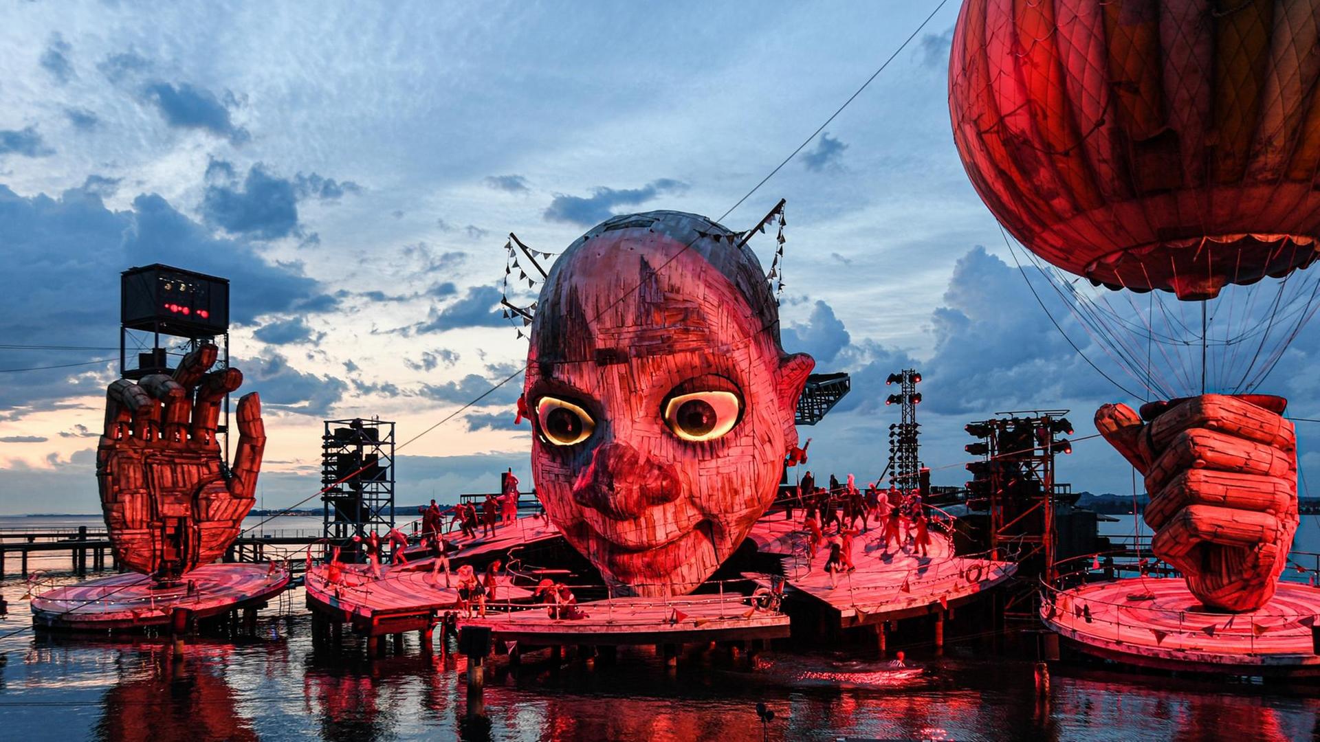 Ein riesiger Kopf mitten im See ist das Bühnenbild von Rigoletto auf der Seebühne Bregenz Ein riesiger Kopf mitten im See ist das Bühnenbild von Rigoletto auf der Seebühne Bregenz