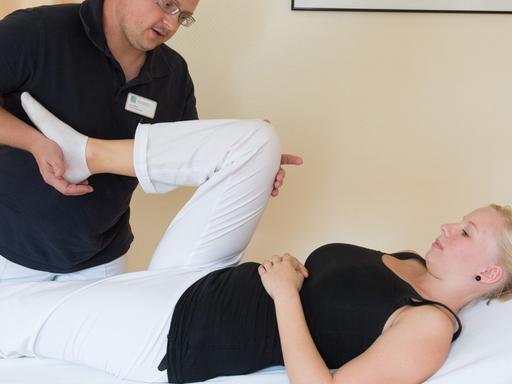 Ein Physiotherapeut behandelt Knieprobleme einer jungen Patientin.
