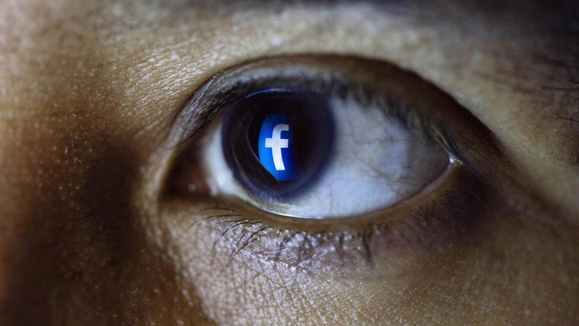 Tablet-Benutzer blickt auf ein Facebook-Logo Tablet-Benutzer blickt auf ein Facebook-Logo