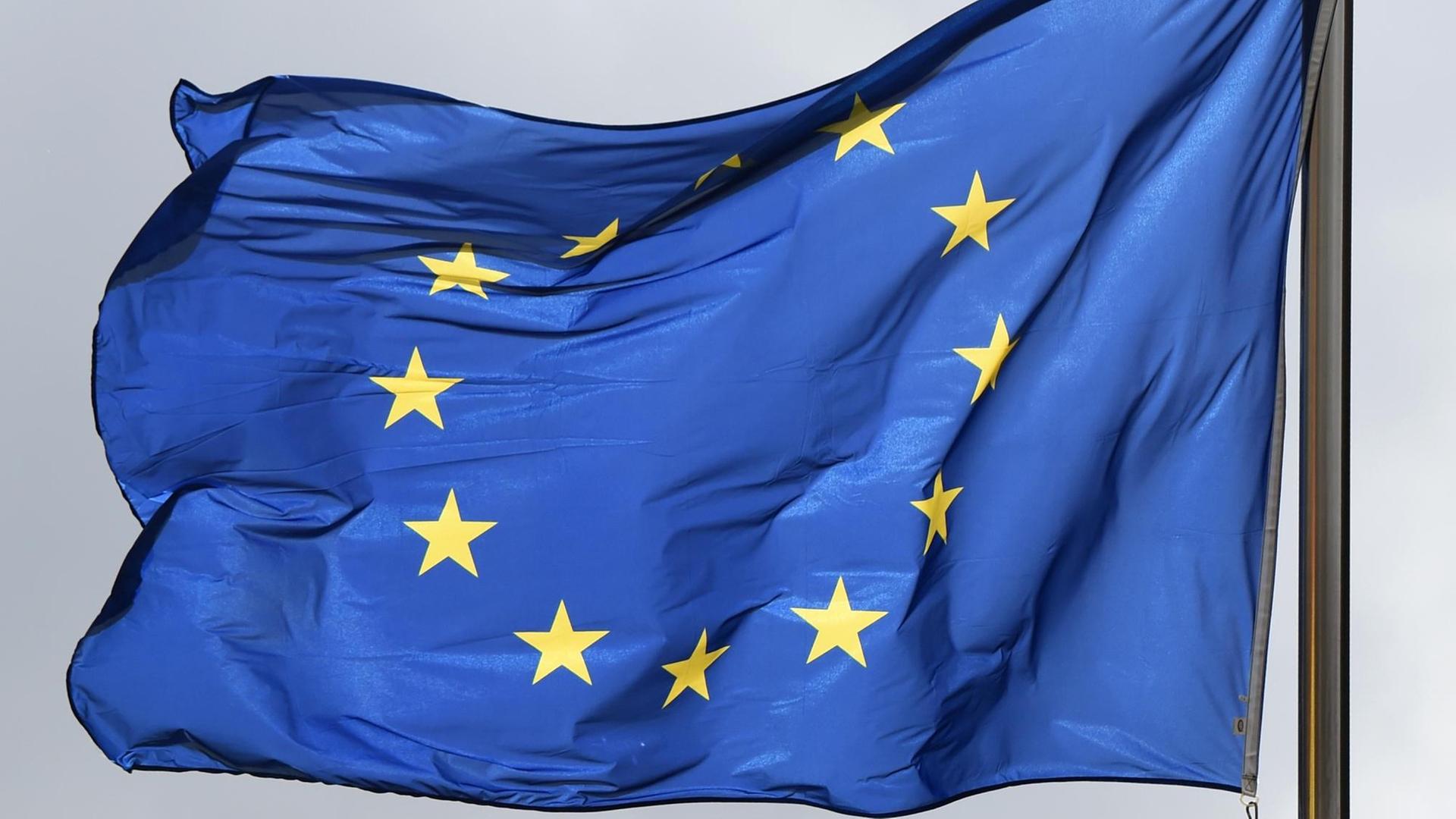 Die blaue Europaflagge mit 12 gelben Sternen im Kreis weht im Wind.