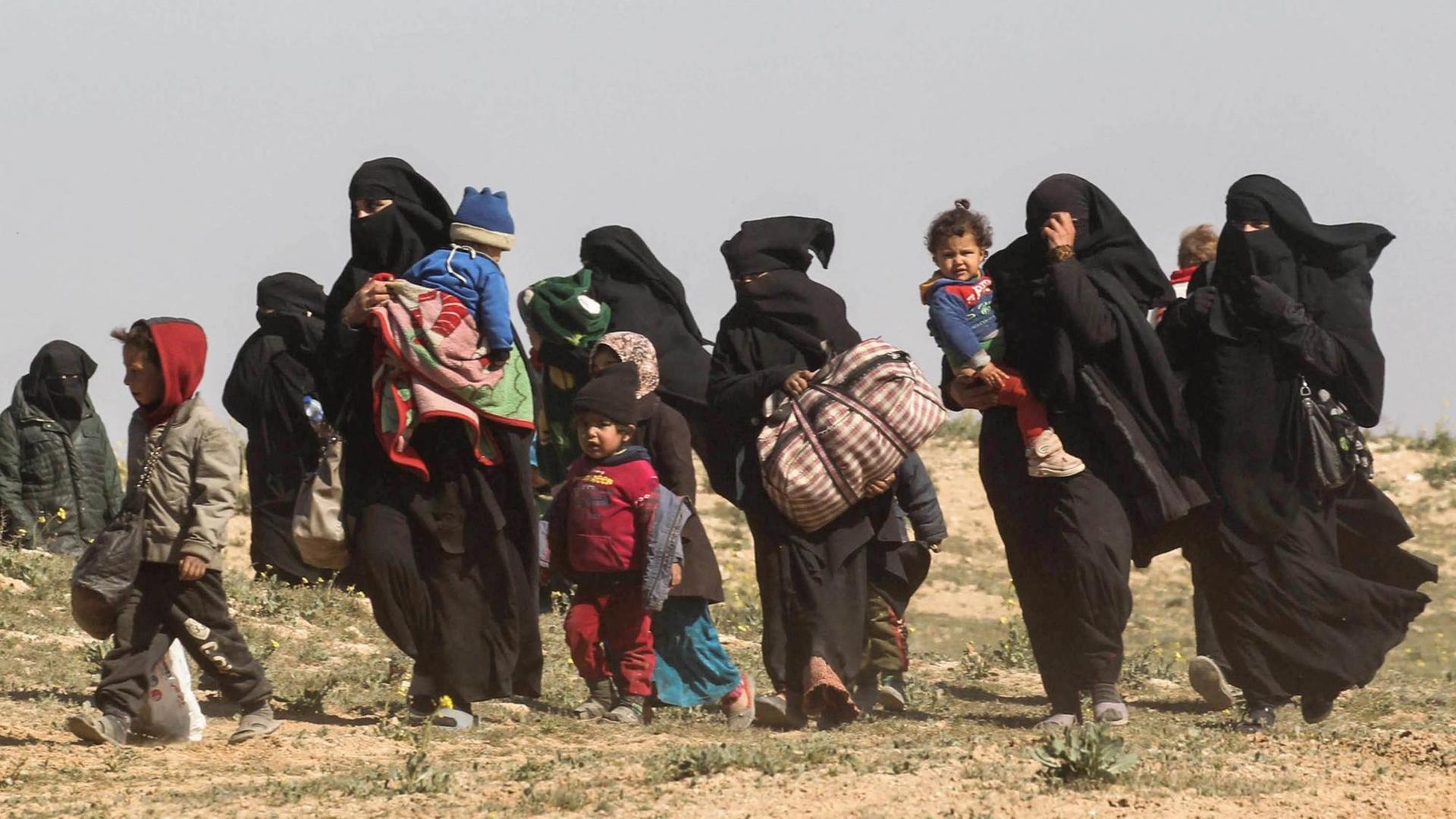 Frauen fliehen mit ihren Kindern aus dem IS-Dorf Baghus im Osten des Landes. Frauen fliehen mit ihren Kindern aus dem IS-Dorf Baghus im Osten des Landes.