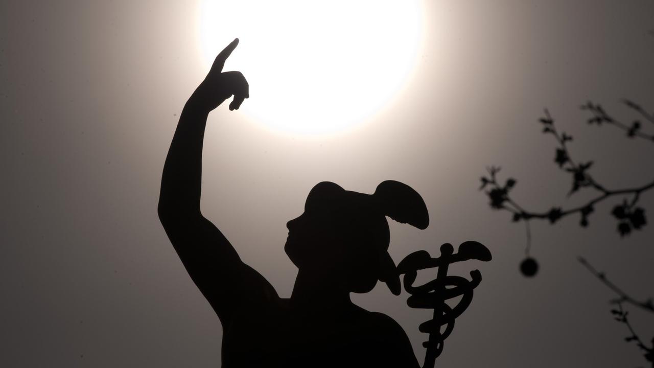 Die Sonne scheint am 03.04.2014 in Stuttgart (Baden-Württemberg) hinter einer Merkur-Statue. Winzige Sandkörner aus der Sahara sollen die Sonne in den kommenden Tagen milchig erscheinen lassen.