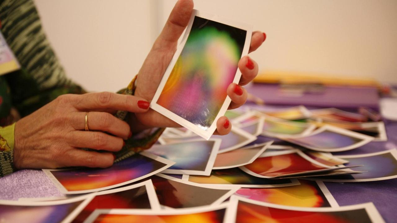 Die Hand einer Wahrsagerin zeigt auf ein Foto mit einer Aura Fotografie. Die Hand einer Wahrsagerin zeigt auf ein Foto mit einer Aura Fotografie.