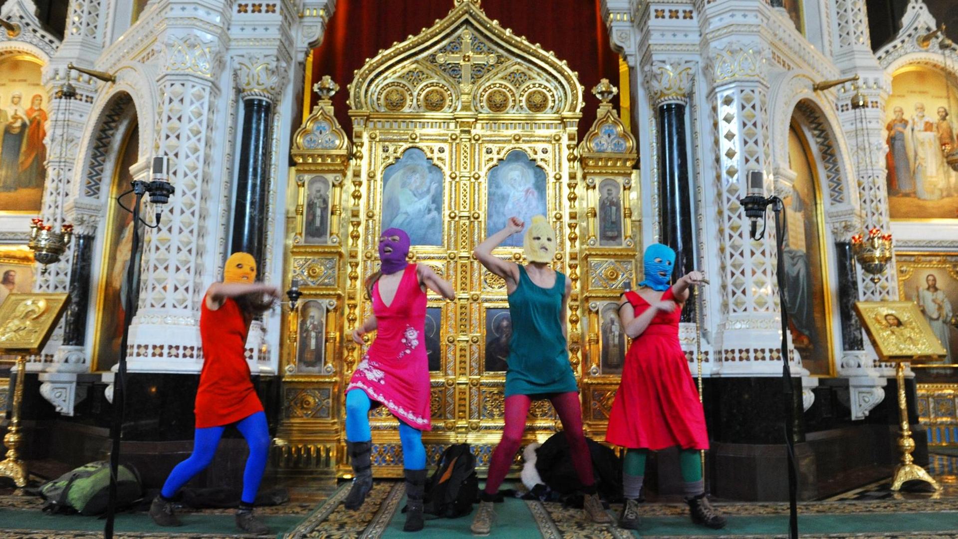 Das Bild zeigt die Musikerinnen von Pussy Riot bei ihrem inzwischen legendären Auftritt in einer Kirche in Moskau mit bunten Sturmhauben. Das Bild zeigt die Musikerinnen von Pussy Riot bei ihrem inzwischen legendären Auftritt in einer Kirche in Moskau mit bunten Sturmhauben.