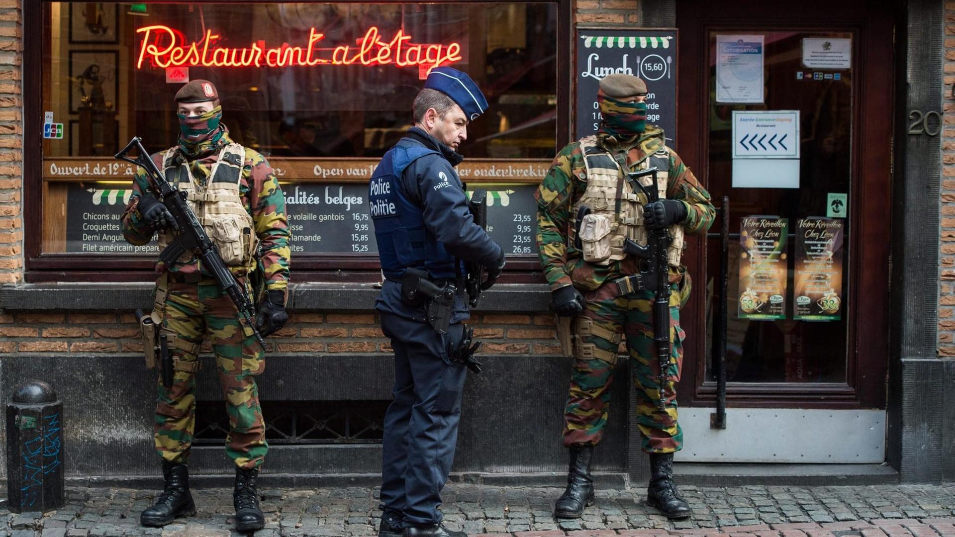 Ein Polizist und zwei Soldaten sichern ein Restaurant in der belgischen Hauptstadt Brüssel. Ein Polizist und zwei Soldaten sichern ein Restaurant in der belgischen Hauptstadt Brüssel.