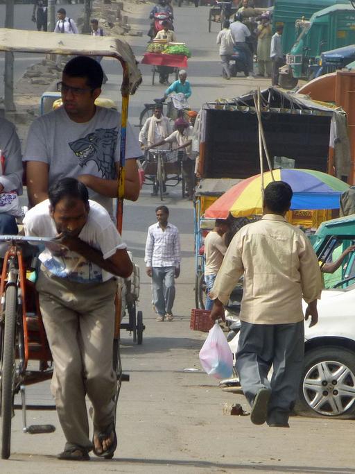 Alltag in Old Delhi: Ein Mann zieht eine Rikscha samt Passagieren.