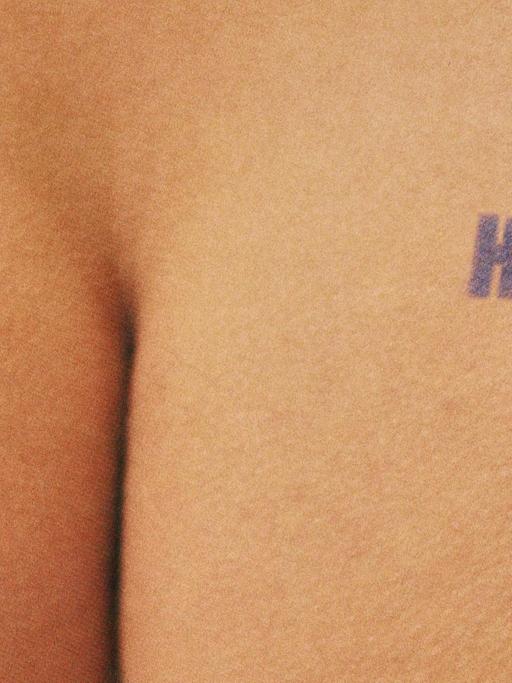 Zu sehen ist ein nacktes Hinterteil, das den Stempel "H.I.V. positiv" trägt. Es handelt sich um eine Werbekampagne von Benetton.