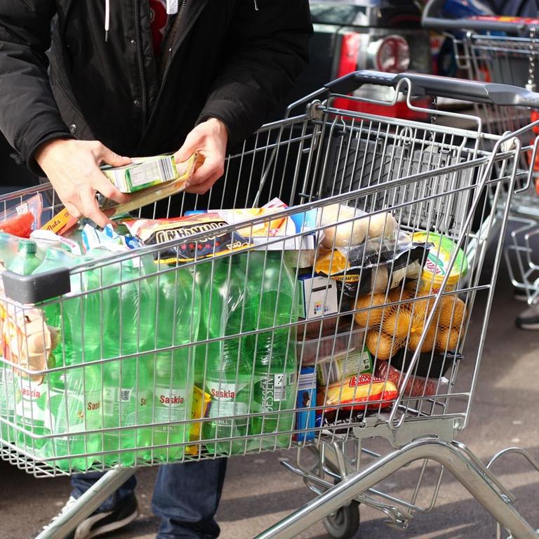 Ein Mann steht am 02.03.2020 mit einem vollen Einkaufswagen vor einem Supermarkt in Berlin.