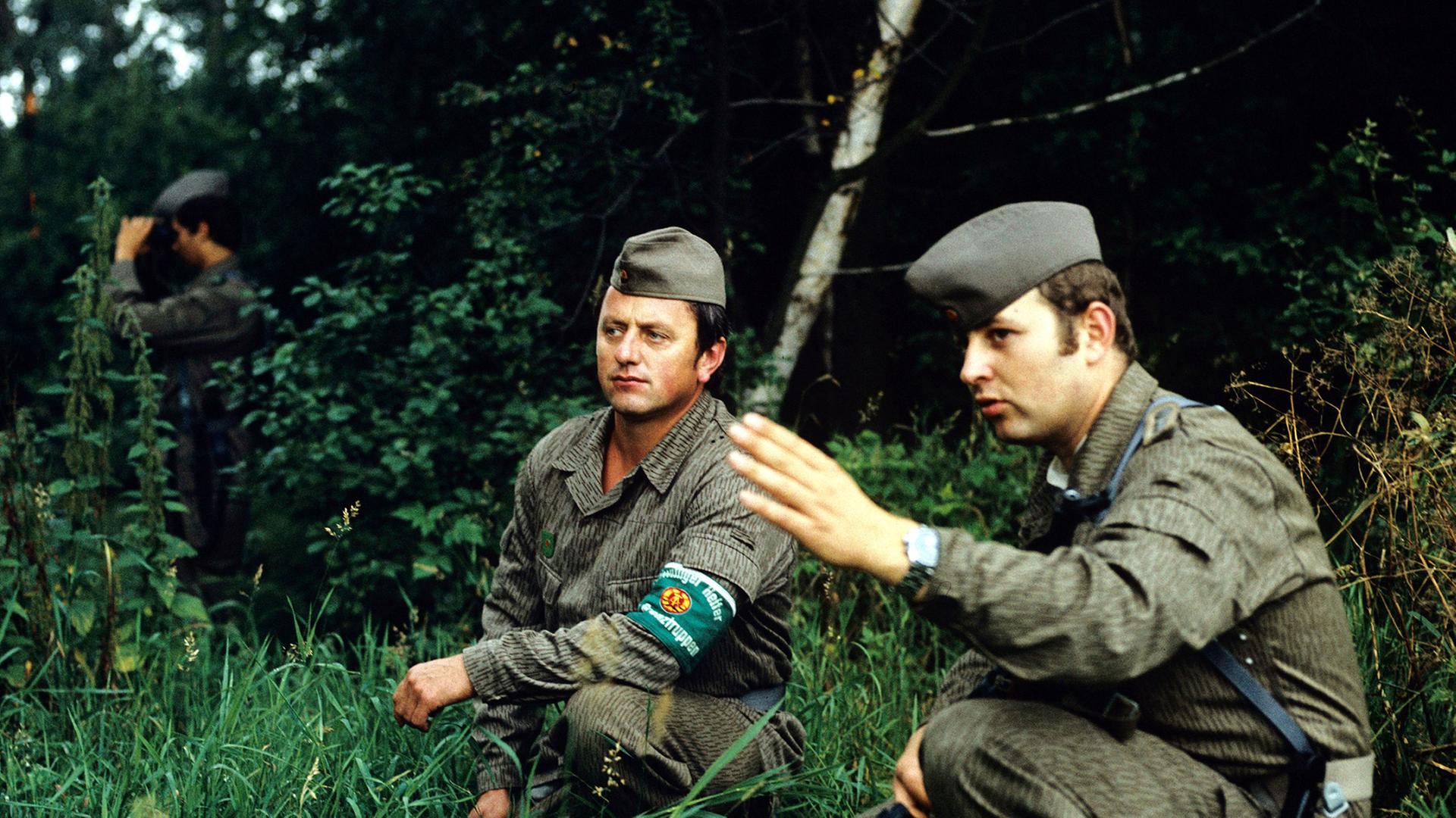 Ein Offizier der DDR-Grenztruppen des Grenzkommandos Süd mit einem "freiwilligen Helfer der Grenztruppen" bei der Beobachtung in einem Abschnitt der innerdeutschen Grenze am Brocken (1987)