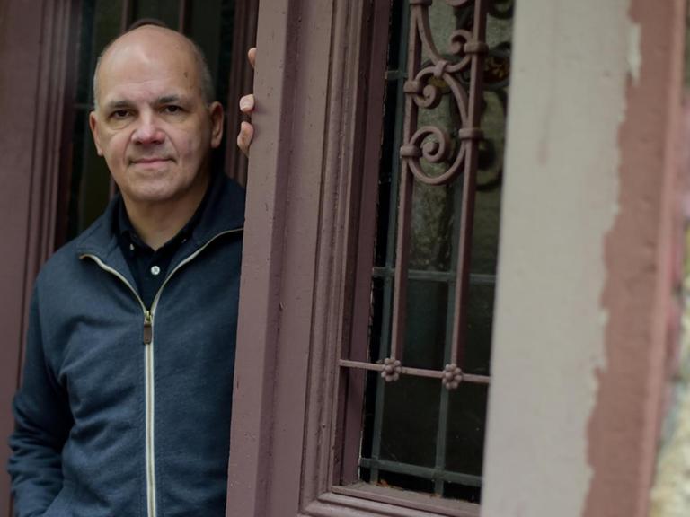 Der Schriftsteller Frank Witzel steht lässig in einem Hauseingang und blickt auf die Straße