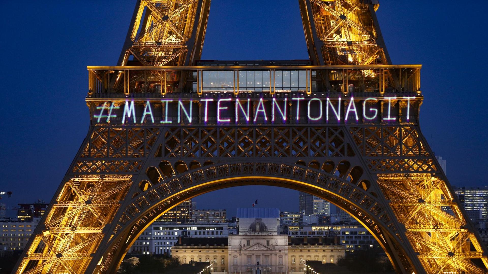 Der Eiffelturm wird mit dem Schriftzug "Maintenant on agit" angeleuchtet. Der Eiffelturm wird mit dem Schriftzug "Maintenant on agit" angeleuchtet.