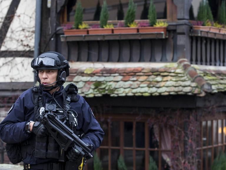 Ein Polizist mit einer Maschinenpistole steht vor einem historischen Fachwerkgebäude in Straßburg