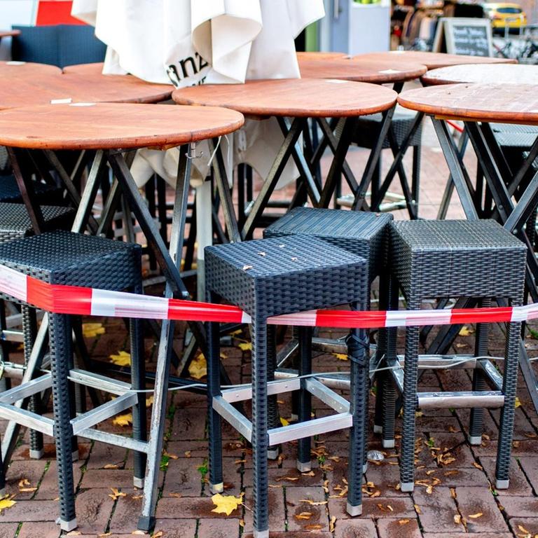 Mit Flatterband abgesperrte Tische und Stühle stehen vor einer Pizzeria in der Corona-Pandemie.
