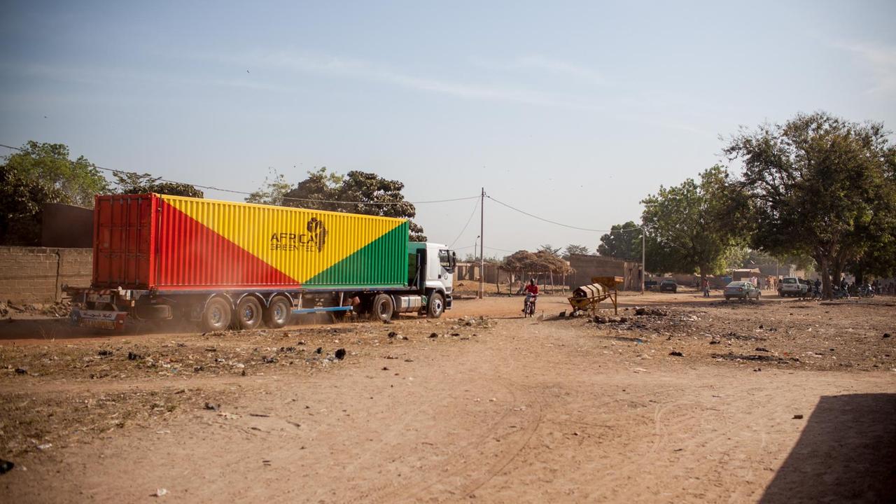Der Container des deutschen Start-ups "Africa GrenTec" fährt durch das malische Djoliba in der Koulikoro-Region. Steine und wüstenähnliche Vegetation sind zu sehen.