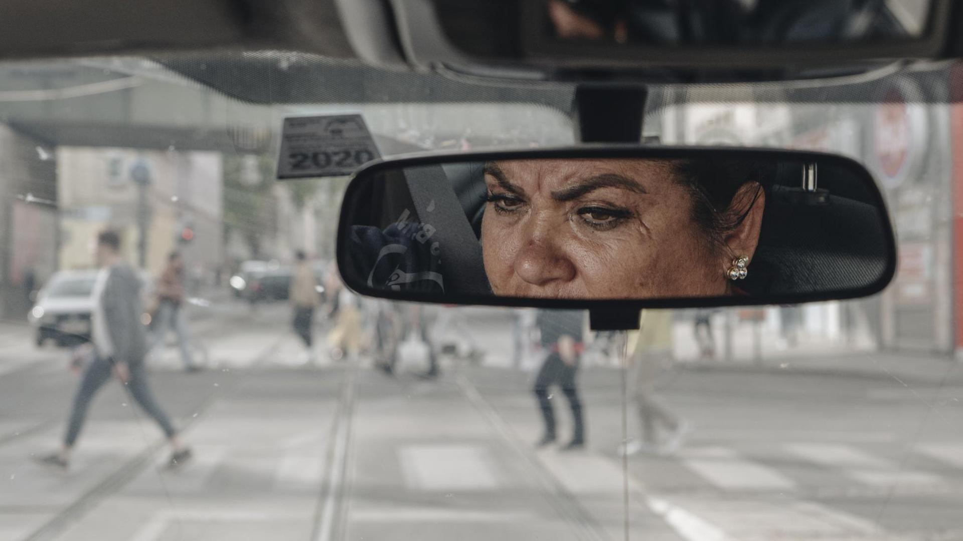 Das Gesicht einer Frau ist im Rückspiegel ihres Autos zu sehen. Das Gesicht einer Frau ist im Rückspiegel ihres Autos zu sehen.