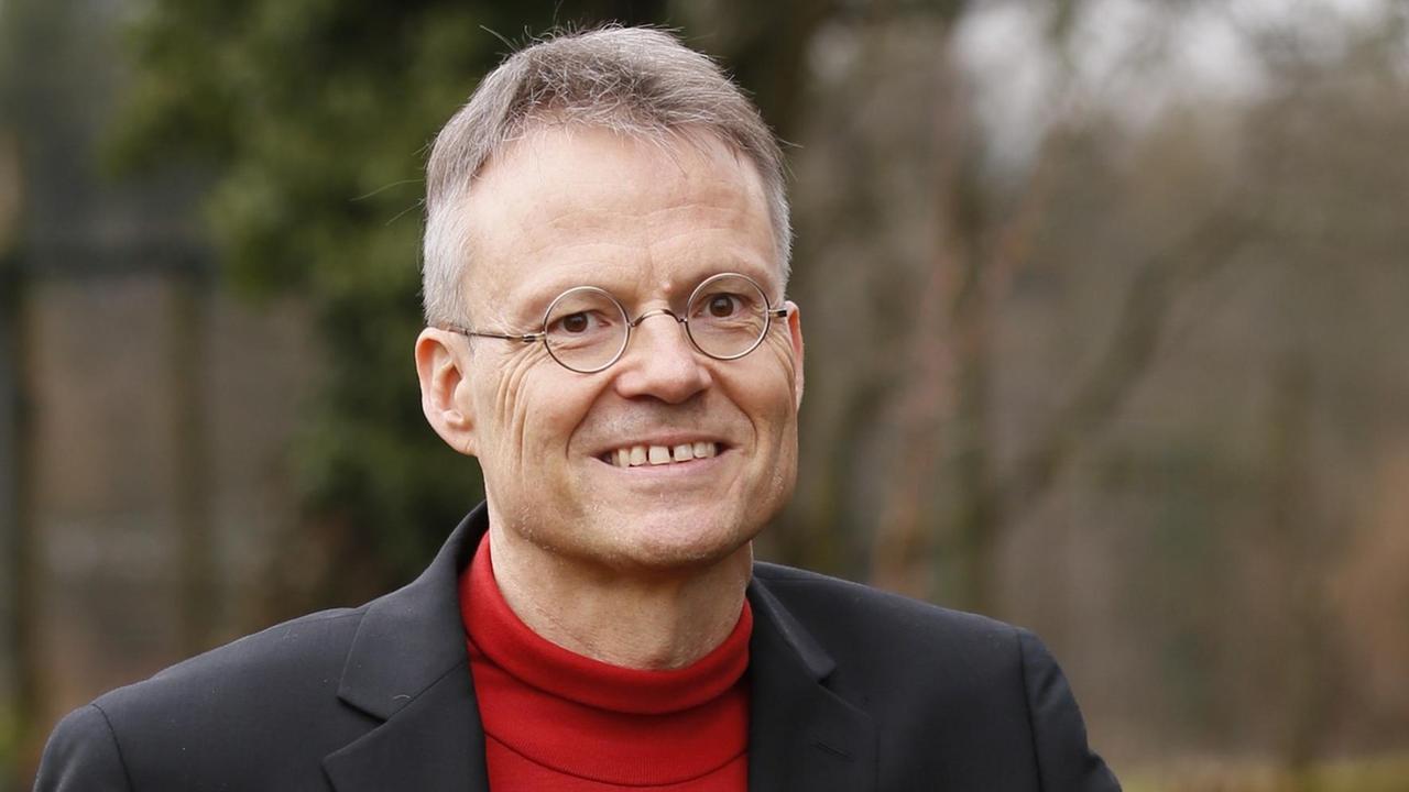 Porträt des Physikers Markolf Niemz, im Freien, schwarzes Sakko und roter Rollkragenpullover, im Hintergrund Bäume in einem Park Porträt des Physikers Markolf Niemz, im Freien, schwarzes Sakko und roter Rollkragenpullover, im Hintergrund Bäume in einem Park