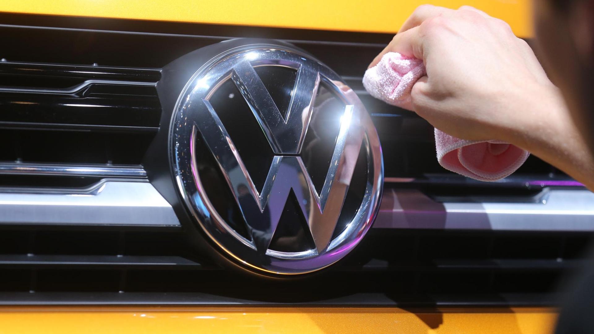 Ein Mitarbeiter von Volkswagen poliert am 12.03.2015 in Berlin vor Beginn der Jahres-Pressekonferenz das Logo an einem VW Sport Coupe. Ein Mitarbeiter von Volkswagen poliert am 12.03.2015 in Berlin vor Beginn der Jahres-Pressekonferenz das Logo an einem VW Sport Coupe.