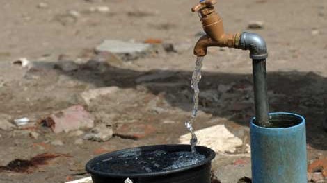 Wasser läuft in einem Armenviertel von Kapstadt in einen Eimer Wasser läuft in einem Armenviertel von Kapstadt in einen Eimer