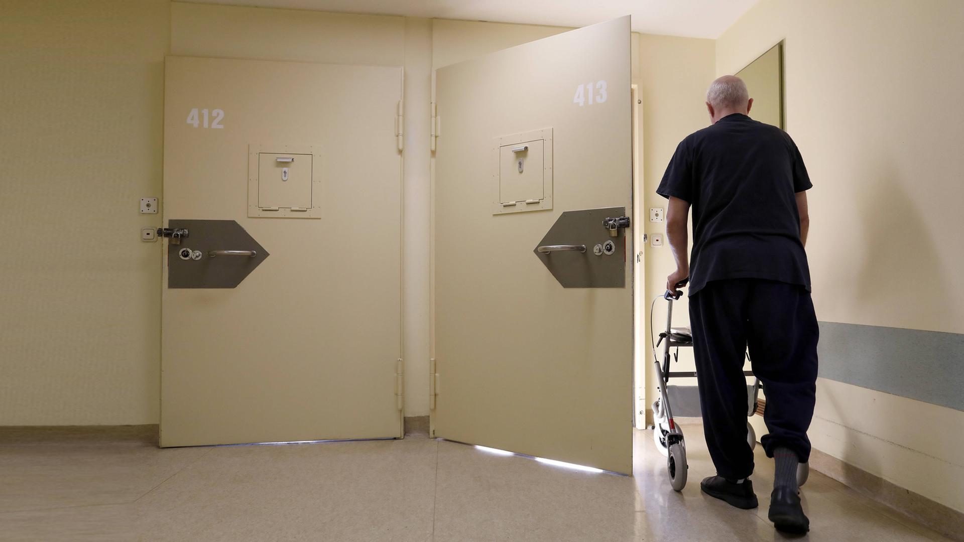 Rückenansicht eines älteren Mannes, der seinen Rollator, einen Gang entlang schiebt. Rückenansicht eines älteren Mannes, der seinen Rollator, einen Gang entlang schiebt.