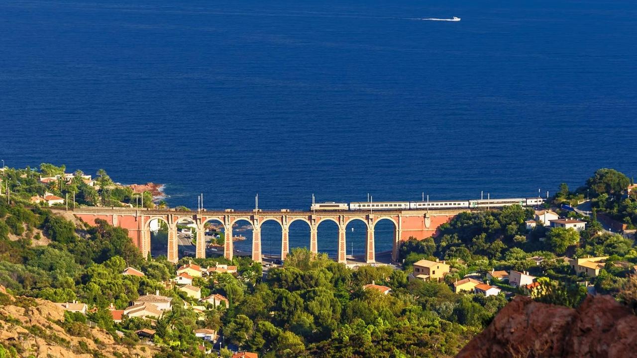 Ein Zug fährt in Südfrankreich entlang der Küste über ein altes Viadukt mit direktem Blick auf das offene Meer. Ein Zug fährt in Südfrankreich entlang der Küste über ein altes Viadukt mit direktem Blick auf das offene Meer.
