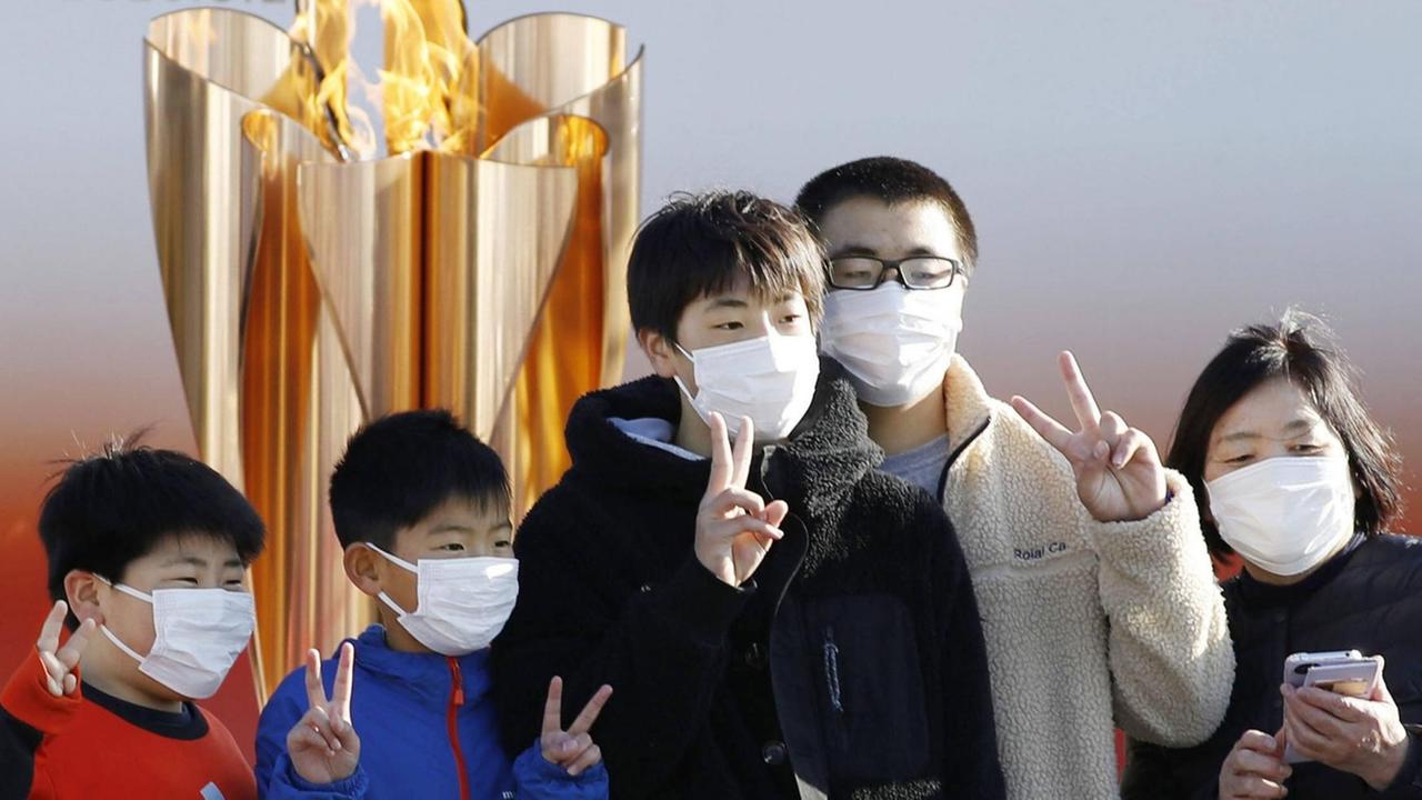 Junge Japaner posieren mit dem Victory-Zeichen vor der Olympischen Flamme im Nordosten des Landes. Junge Japaner posieren mit dem Victory-Zeichen vor der Olympischen Flamme im Nordosten des Landes.
