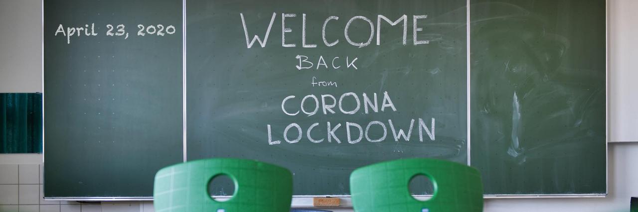 Ein leeres Klassenzimmer mit grünen Stühlen und einer Tafel, auf der steht: "Welcome Back From Corona Lockdown"- Ein leeres Klassenzimmer mit grünen Stühlen und einer Tafel, auf der steht: "Welcome Back From Corona Lockdown"-