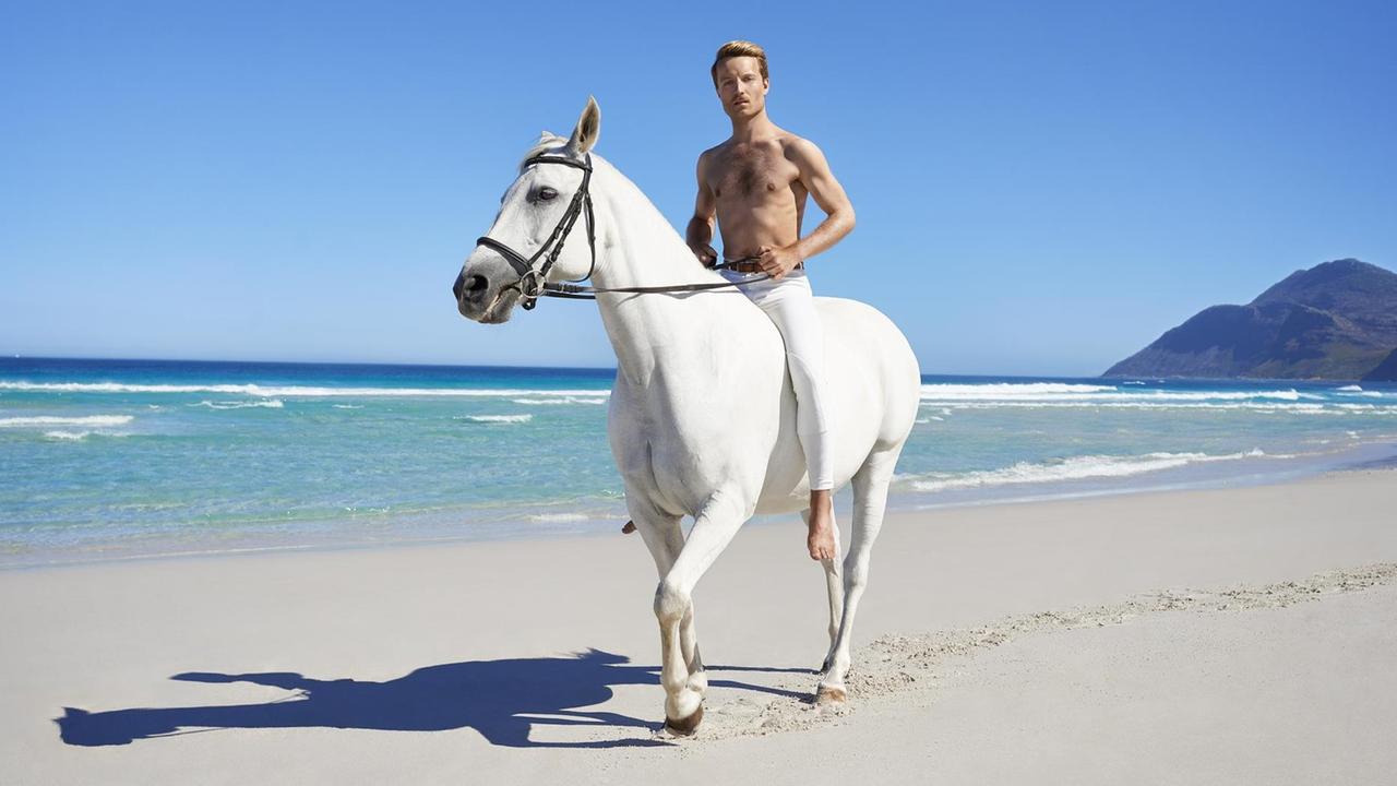 Andy Kassier auf einem weißen Pferd am Strand. Andy Kassier auf einem weißen Pferd am Strand.