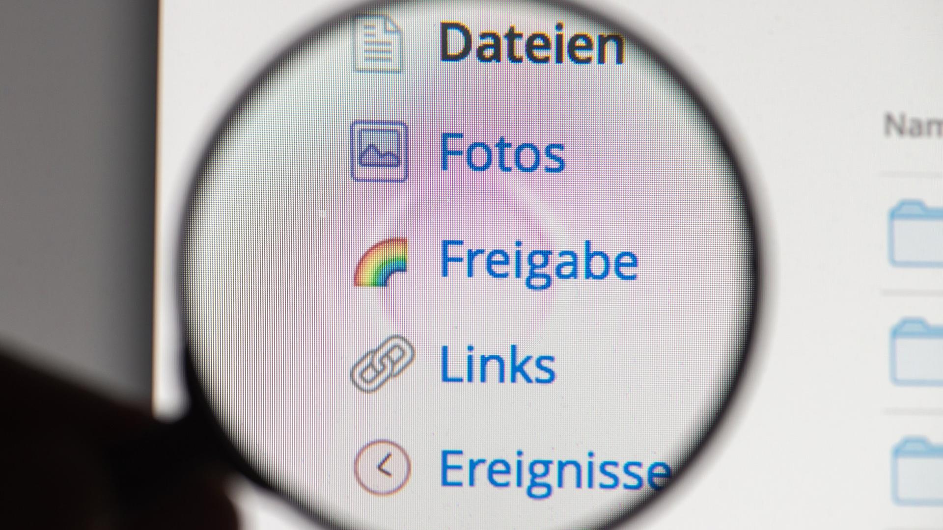 Eine Hand hält in Vergrößerungsglas vor die Internetseite des Online-Speicherdienstes Dropbox. Eine Hand hält in Vergrößerungsglas vor die Internetseite des Online-Speicherdienstes Dropbox.