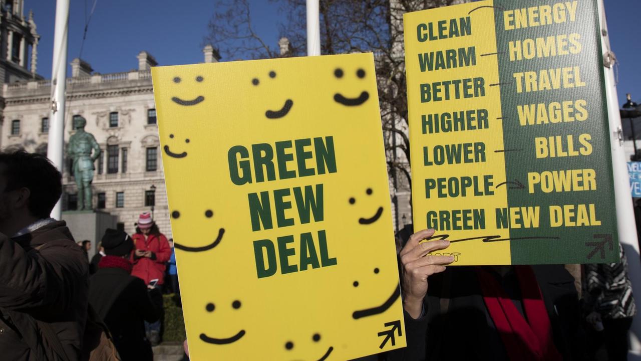 Demonstranten halten ein Plakat mit Smileys und der Aufschrift "Green New Deal".
