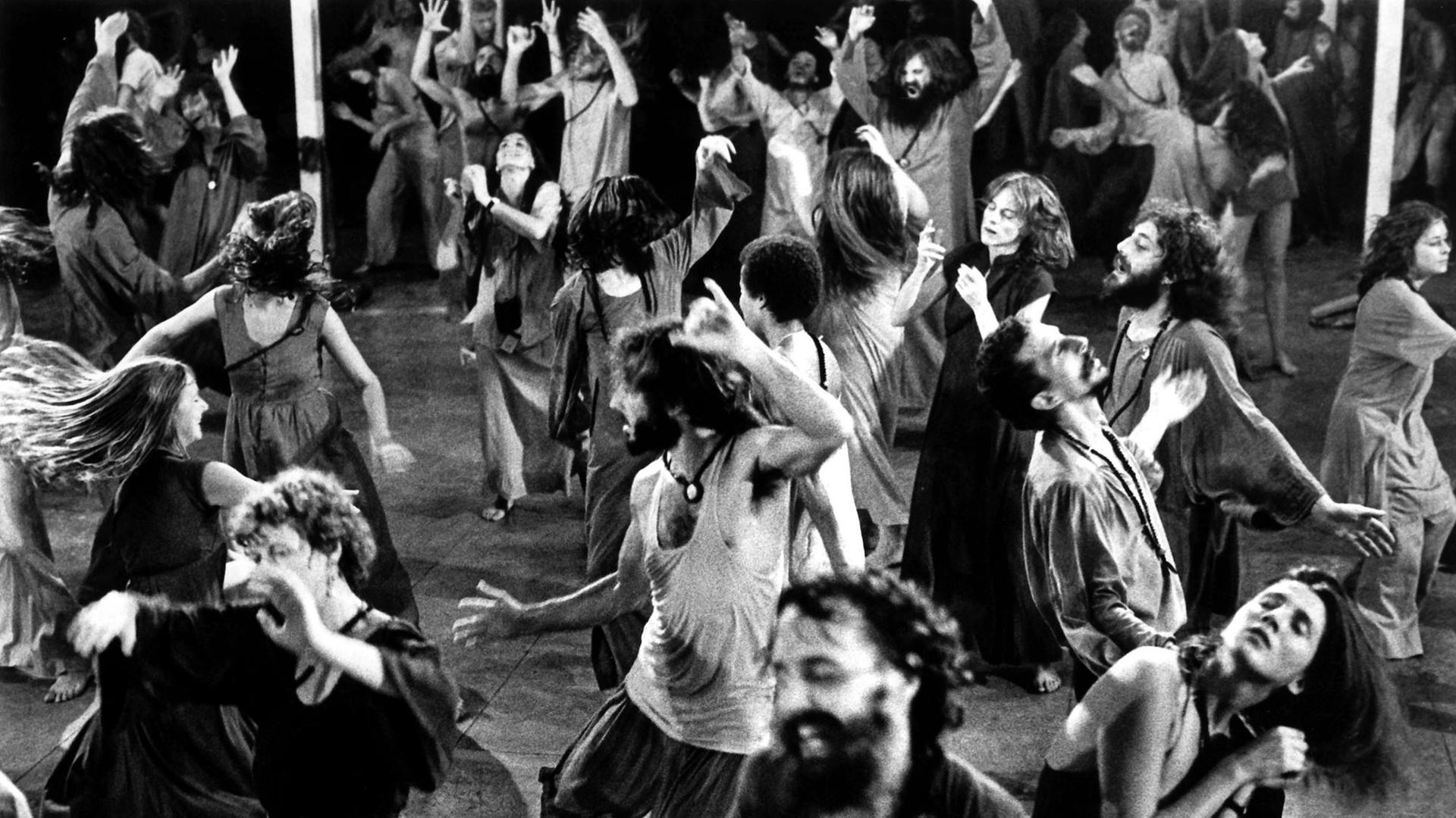 Anhänger aus aller Welt des indischen Gurus und Sektenführers Bhagwan Shree Rajneesh tanzen 1981 während der abendlichen Meditationsstunde im Ashram in Poona in Indien.