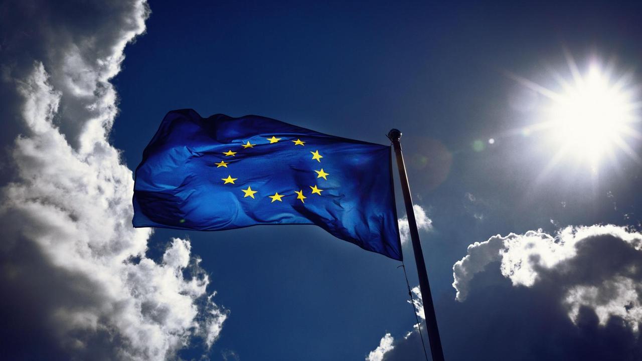 Die Fahne der Europäischen Union weht im Wind und wird von der Sonne angestrahlt. Gewitterwolken ziehen vorbei. Die Fahne der Europäischen Union weht im Wind und wird von der Sonne angestrahlt. Gewitterwolken ziehen vorbei.
