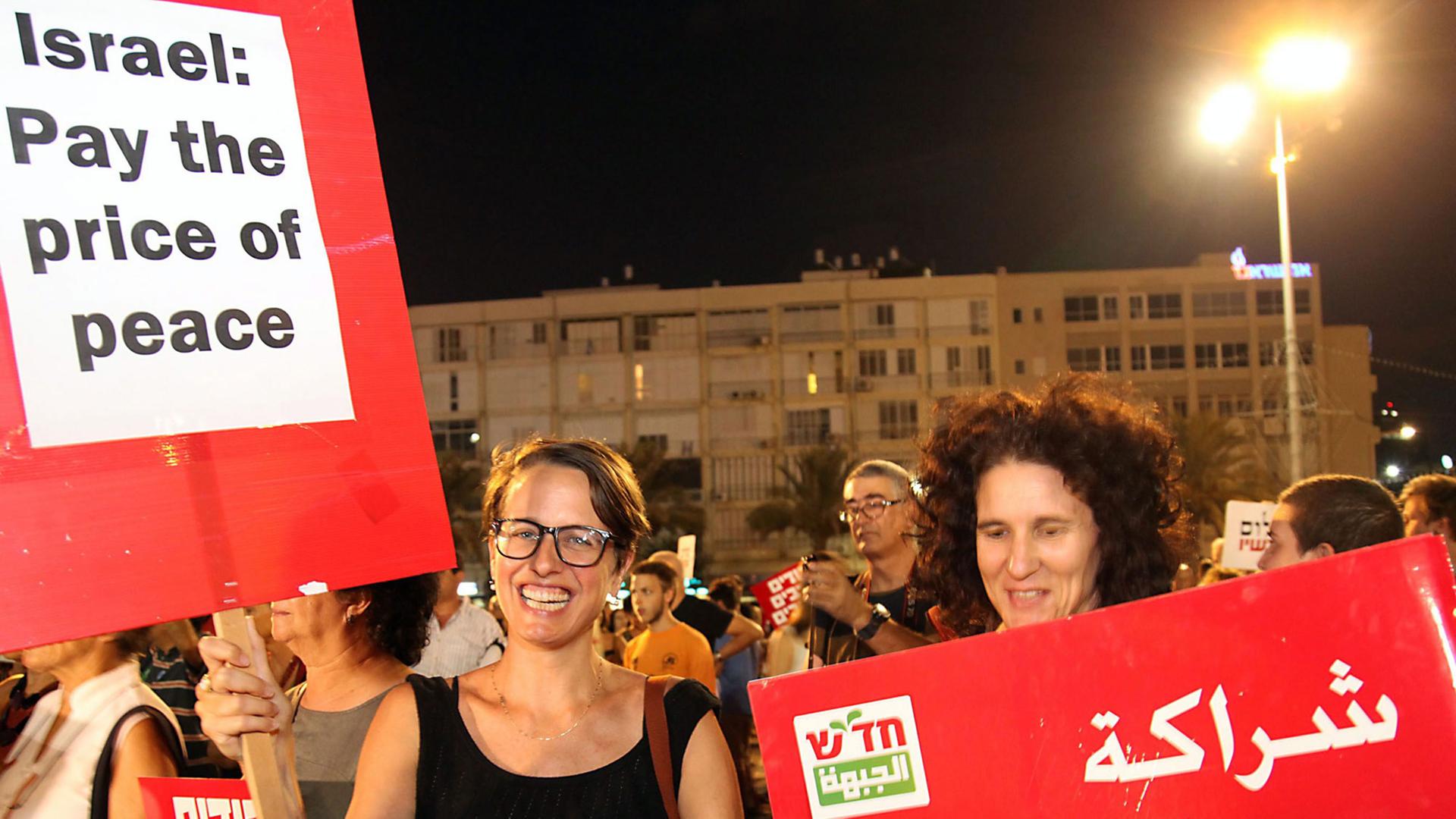 Israelische Demonstranten fordern halten Schilder mit der Aufschrift "Israel: Pay the price of peace" in Englisch und Arabisch auf dem Tel Aviver Rabin-Platz am 16. August 2014. Sie fordern Frieden zwischen Israelis und Palästinensern. Israelische Demonstranten fordern halten Schilder mit der Aufschrift "Israel: Pay the price of peace" in Englisch und Arabisch auf dem Tel Aviver Rabin-Platz am 16. August 2014. Sie fordern Frieden zwischen Israelis und Palästinensern.