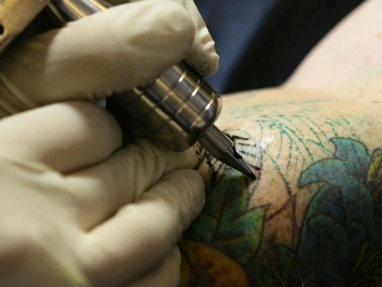 Ein Mann lässt sich ein Tattoo stechen.