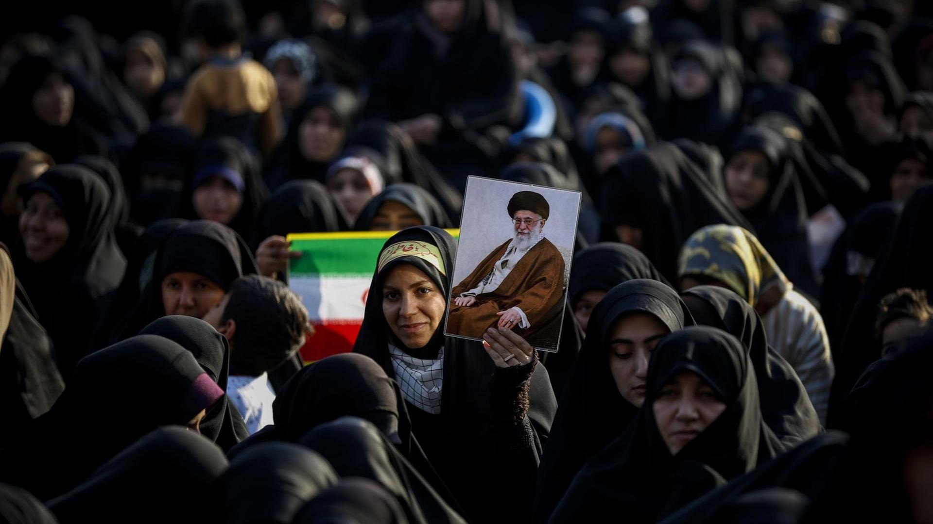 Frauen und Mädchen stehen am 31. Januar 2019 zusammen. Eine hält eine iranische Flagge hoch, eine andere das Bild von Revolutionsführer Ayatollah Khomeini Frauen und Mädchen stehen am 31. Januar 2019 zusammen. Eine hält eine iranische Flagge hoch, eine andere das Bild von Revolutionsführer Ayatollah Khomeini