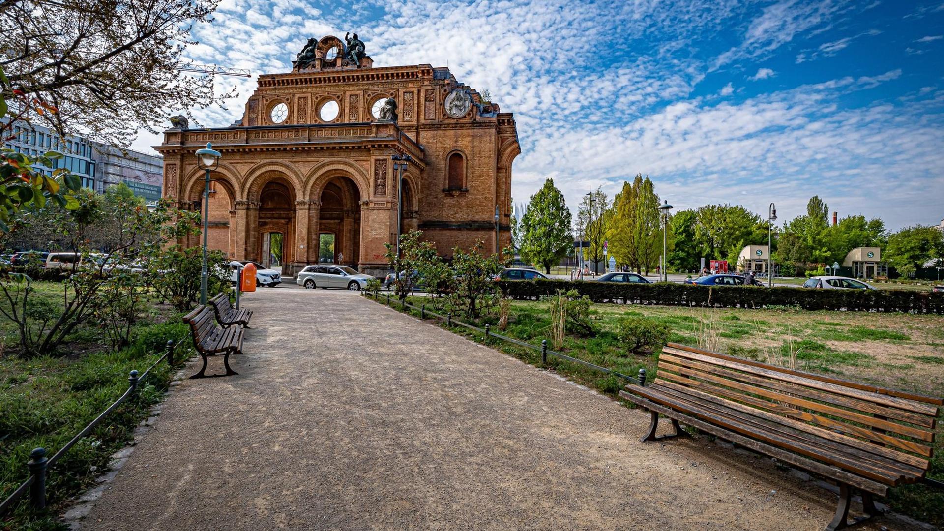 Eine Grünfläche mit einem Spazierweg und Parkbänken. Im Hintergrund die Ruine des Anhalter Bahnhofs. Eine Grünfläche mit einem Spazierweg und Parkbänken. Im Hintergrund die Ruine des Anhalter Bahnhofs.