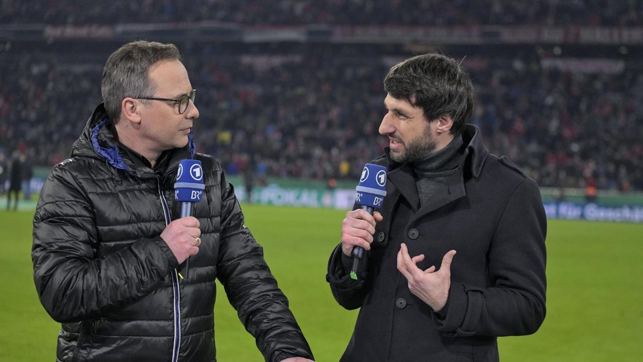 Thomas Broich und Matthias Opdenhövel stehen am 05.02.2020 bei der ARD-Live-Übertragung des DFB Pokal Achtelfinales FC Bayern München gegen TSG Hoffenheim in der Allianz-Arena in München mit Mikrofonen am Spielfeldrand. 
