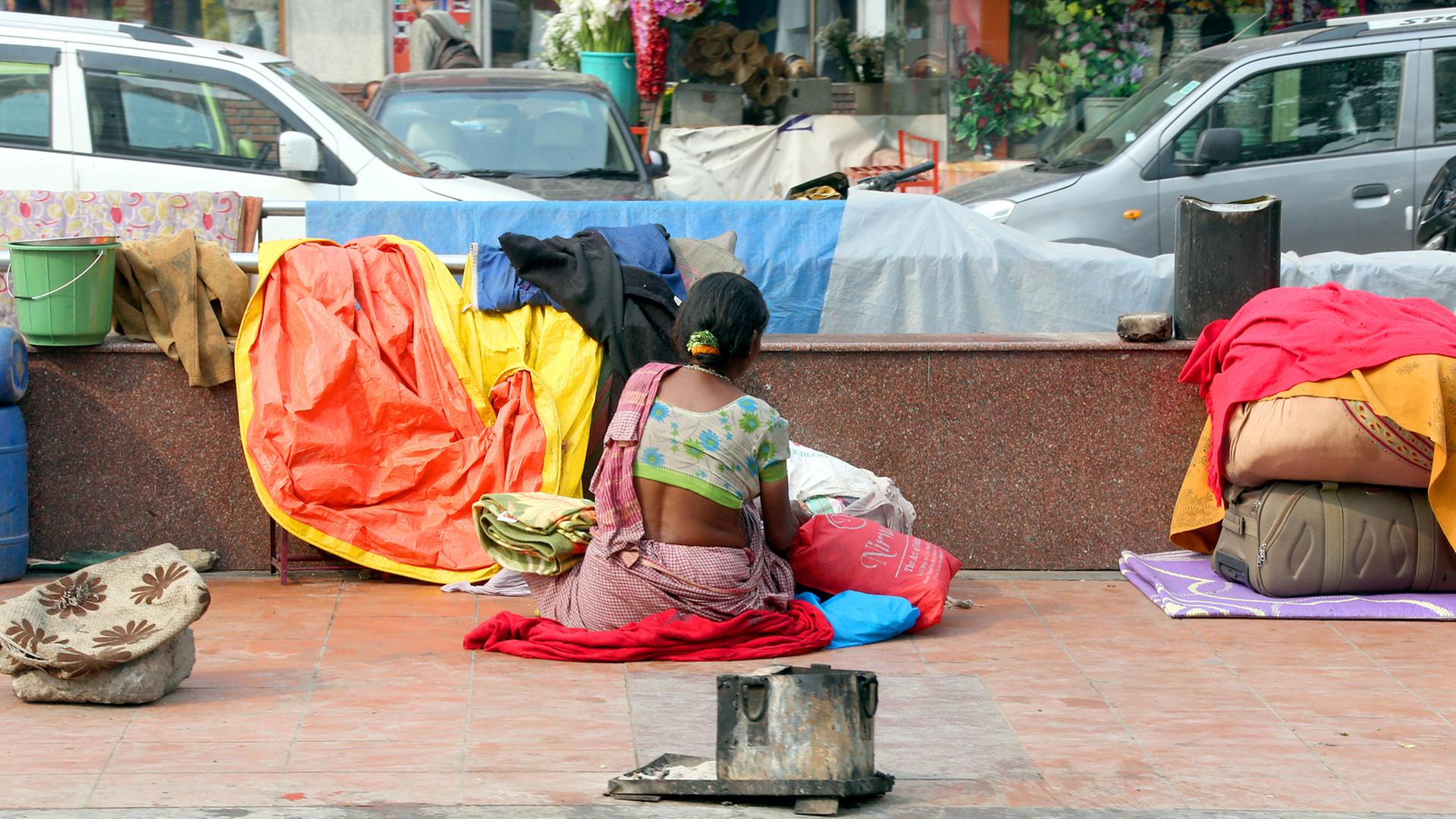 Eine Frau sitzt Old-Delhi in Indien am Straßenrand neben ihrer provisorischen Unterkunft, aufgenommen 2014. Eine Frau sitzt Old-Delhi in Indien am Straßenrand neben ihrer provisorischen Unterkunft, aufgenommen 2014.