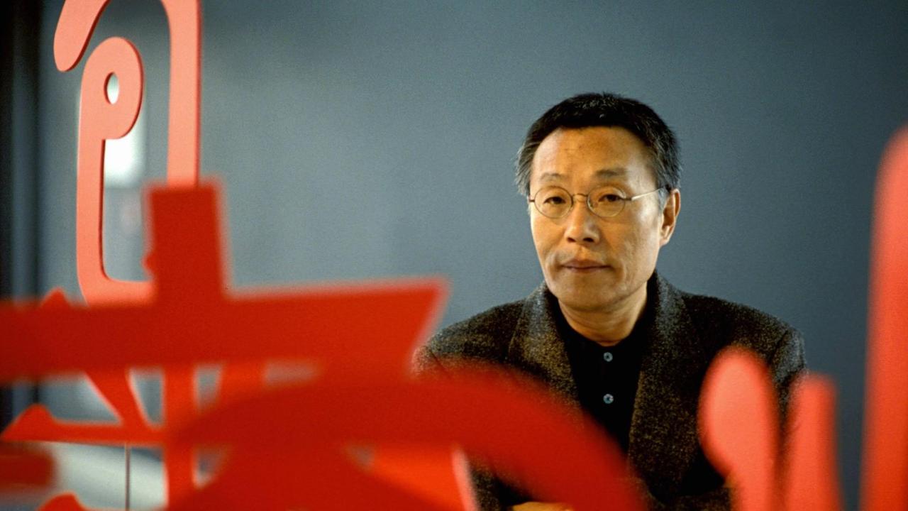 Ein Porträt zeigt den südkoreanischen Schriftsteller Hwang Sok-Yong. Im Vordergrund sind abstrakte rötliche Formen zu erkenne. Ein Porträt zeigt den südkoreanischen Schriftsteller Hwang Sok-Yong. Im Vordergrund sind abstrakte rötliche Formen zu erkenne.