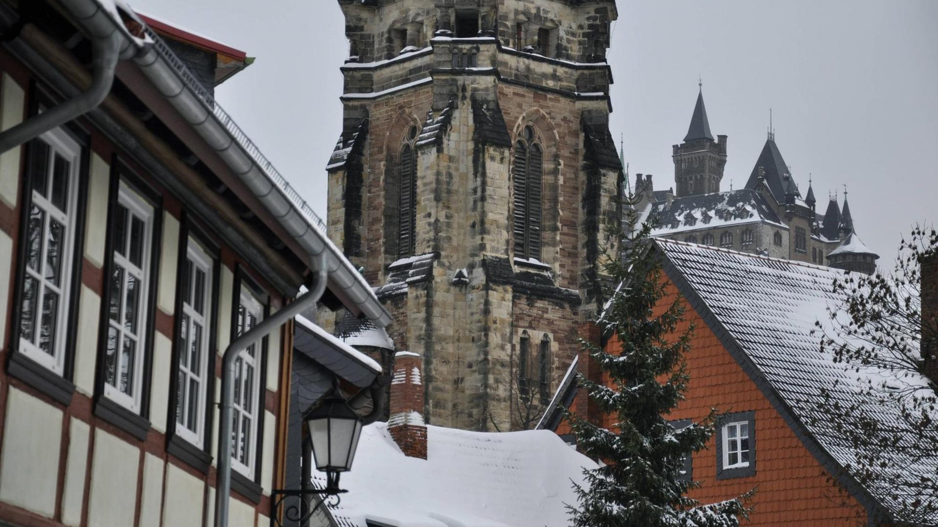 Blick auf Fachwerkhäuser und eine Kirche in Wernigerode im Winter.