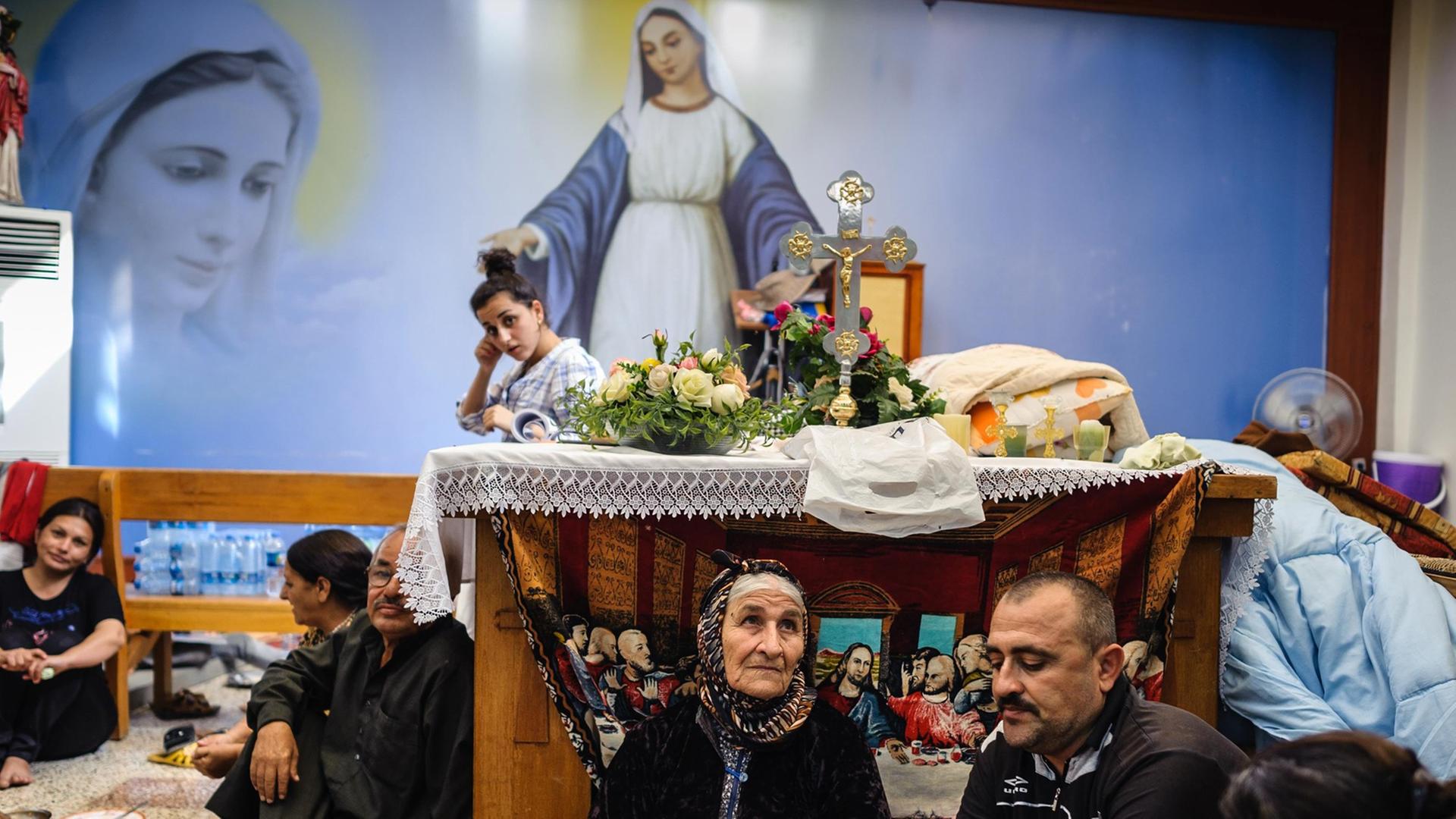 Christen sitzen in einer improvisierten Kirche auf dem Boden