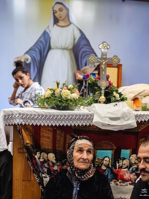 Christen sitzen in einer improvisierten Kirche auf dem Boden