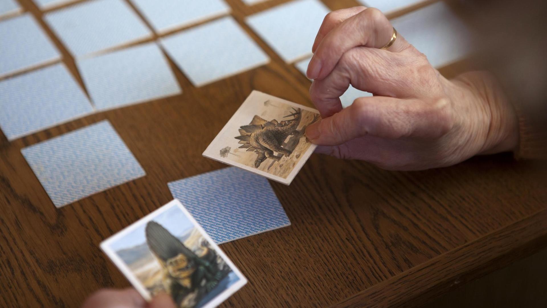 Eine Seniorin spielt Memory: Zu sehen sind die Hände und Spielkarten. Eine Seniorin spielt Memory: Zu sehen sind die Hände und Spielkarten.