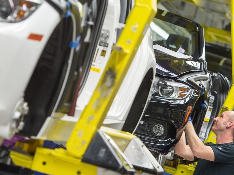 Ein Mann arbeitet im BMW-Werk in Regensburg (Bayern) an einem BMW.