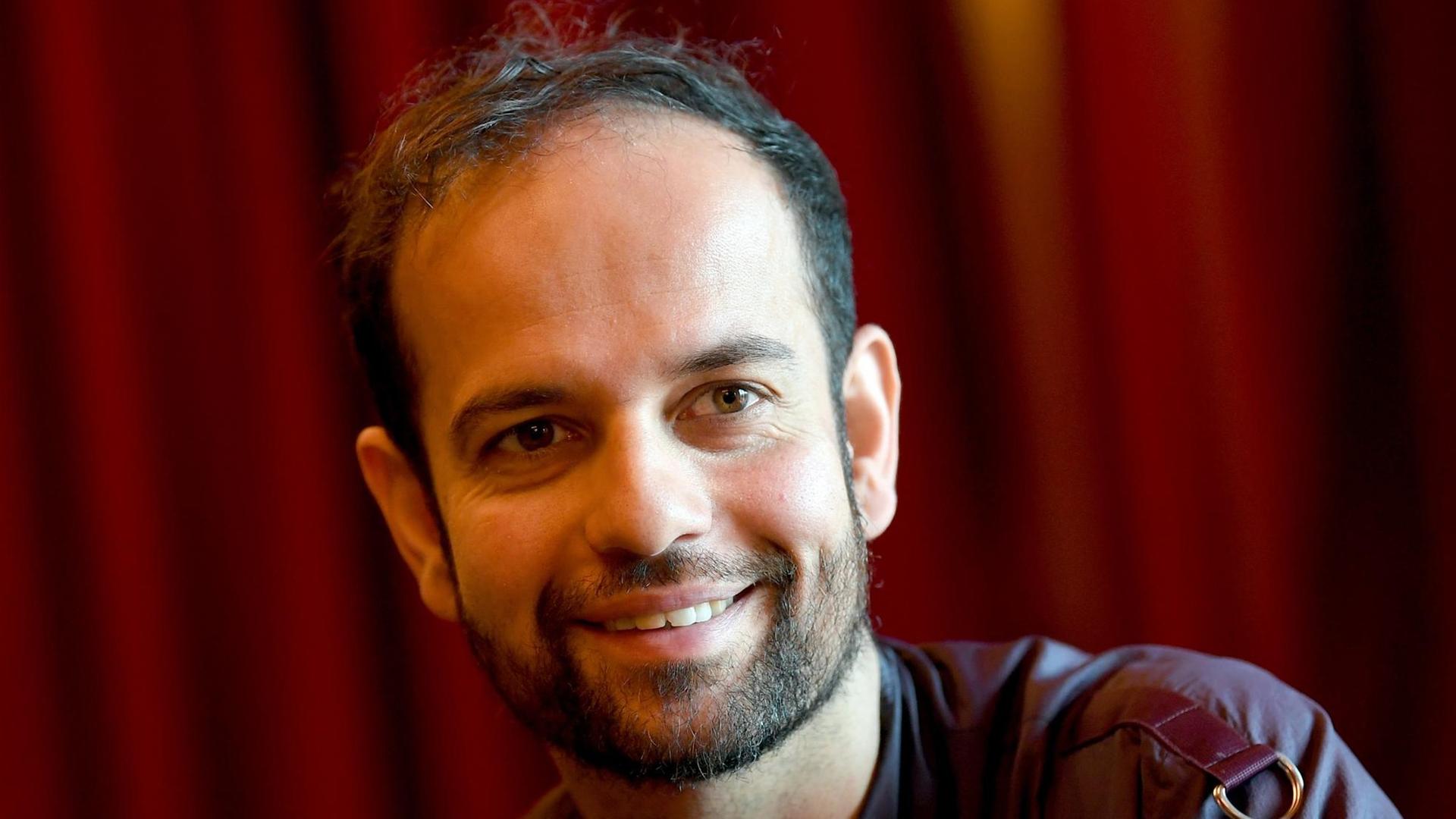 Der Künstler Tino Sehgal aufgenommen am 06.11.2017 in der Volksbühne in Berlin sitzt vor einem roten Vorhang Der Künstler Tino Sehgal aufgenommen am 06.11.2017 in der Volksbühne in Berlin sitzt vor einem roten Vorhang