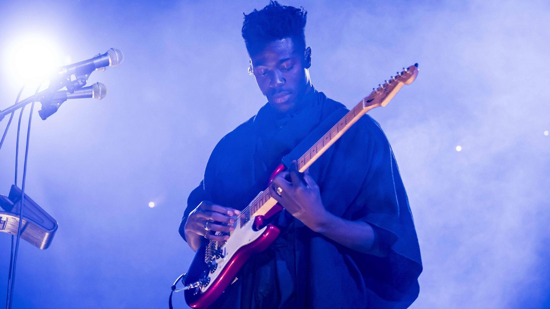Moses Sumney bei einem Auftritt in London im April 2017. Der Sänger spielt Gitarre. Moses Sumney bei einem Auftritt in London im April 2017. Der Sänger spielt Gitarre.