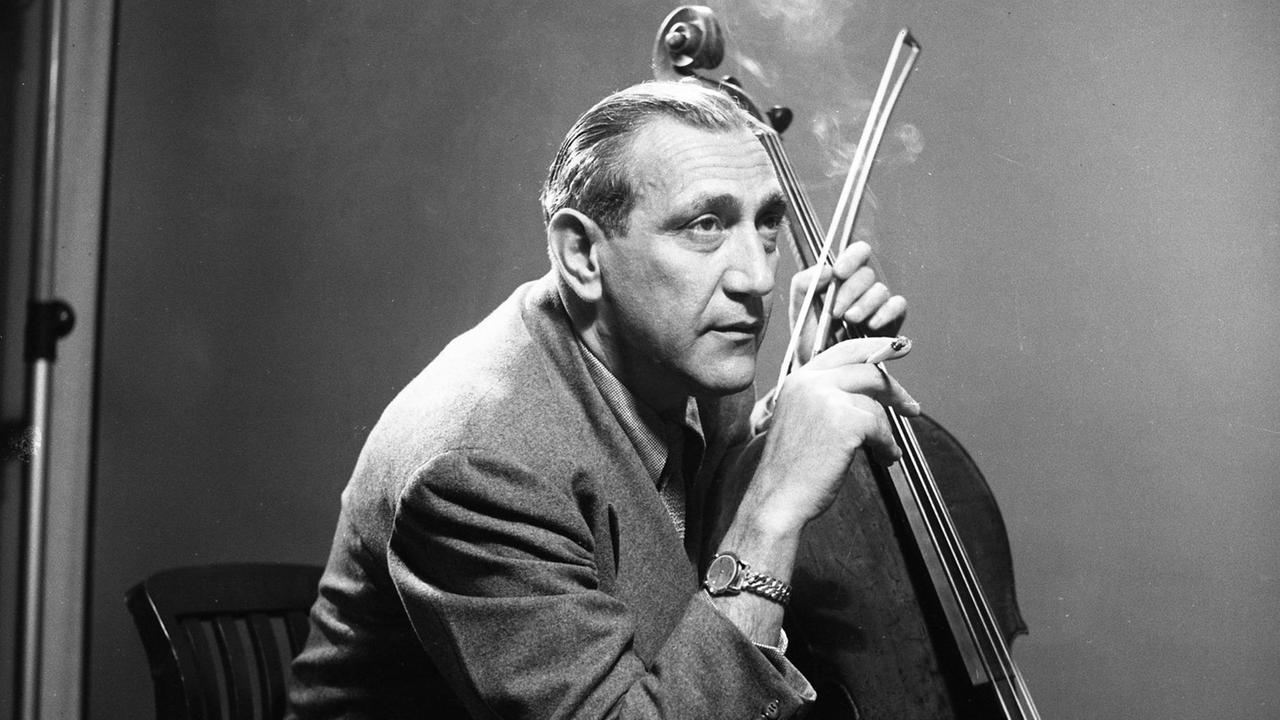 Der Cellist Gregor Piatigorsky im Anzug sitzend mit seinem Cello, in der linken Hand hält er den Bogen, in der rechten Hand eine Zigarette Der Cellist Gregor Piatigorsky im Anzug sitzend mit seinem Cello, in der linken Hand hält er den Bogen, in der rechten Hand eine Zigarette